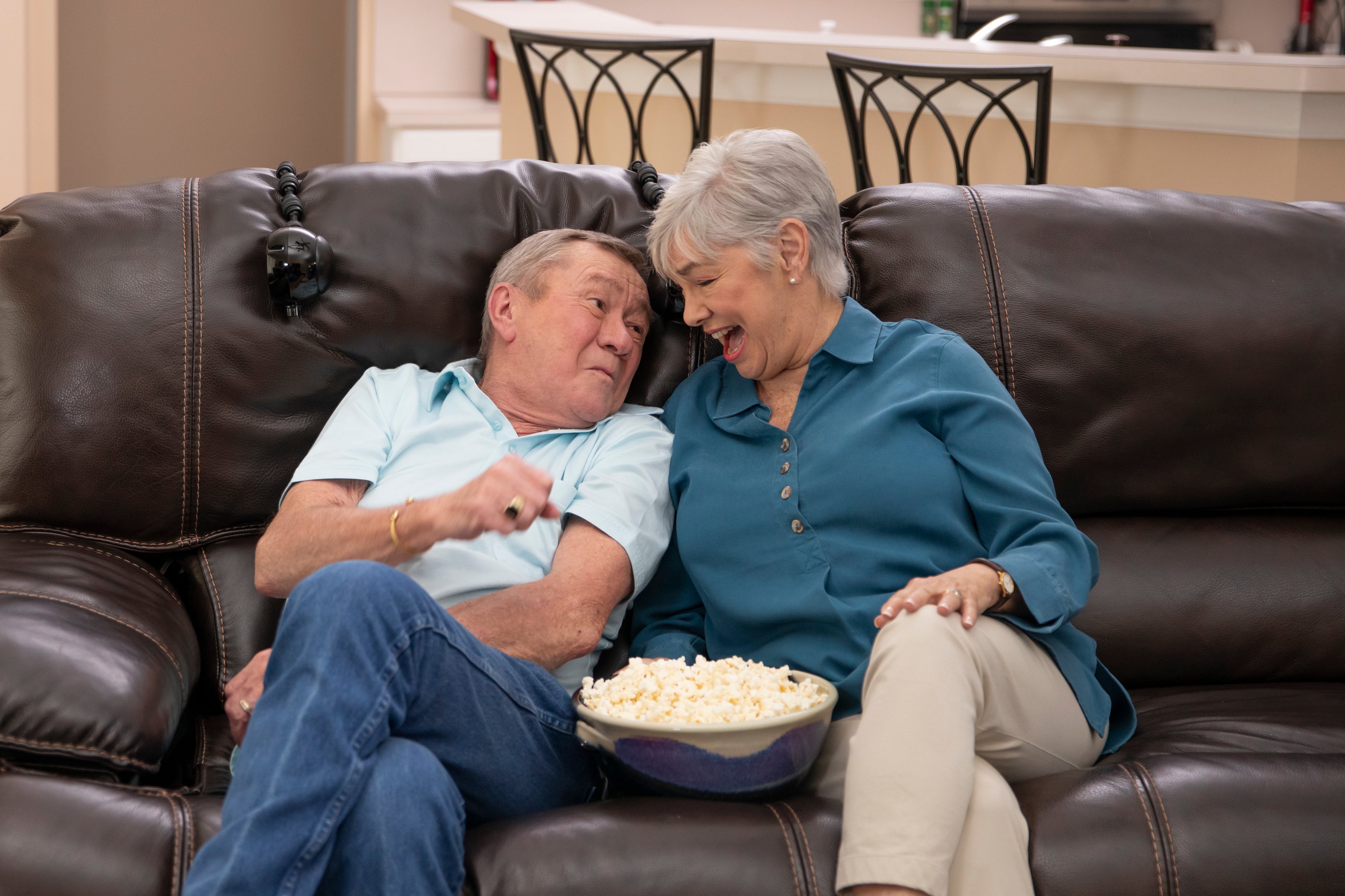 Senior couple enjoying a movie on the sofa with the ChairSpeaker system, showcasing the convenience of personal audio for a shared entertainment experience.